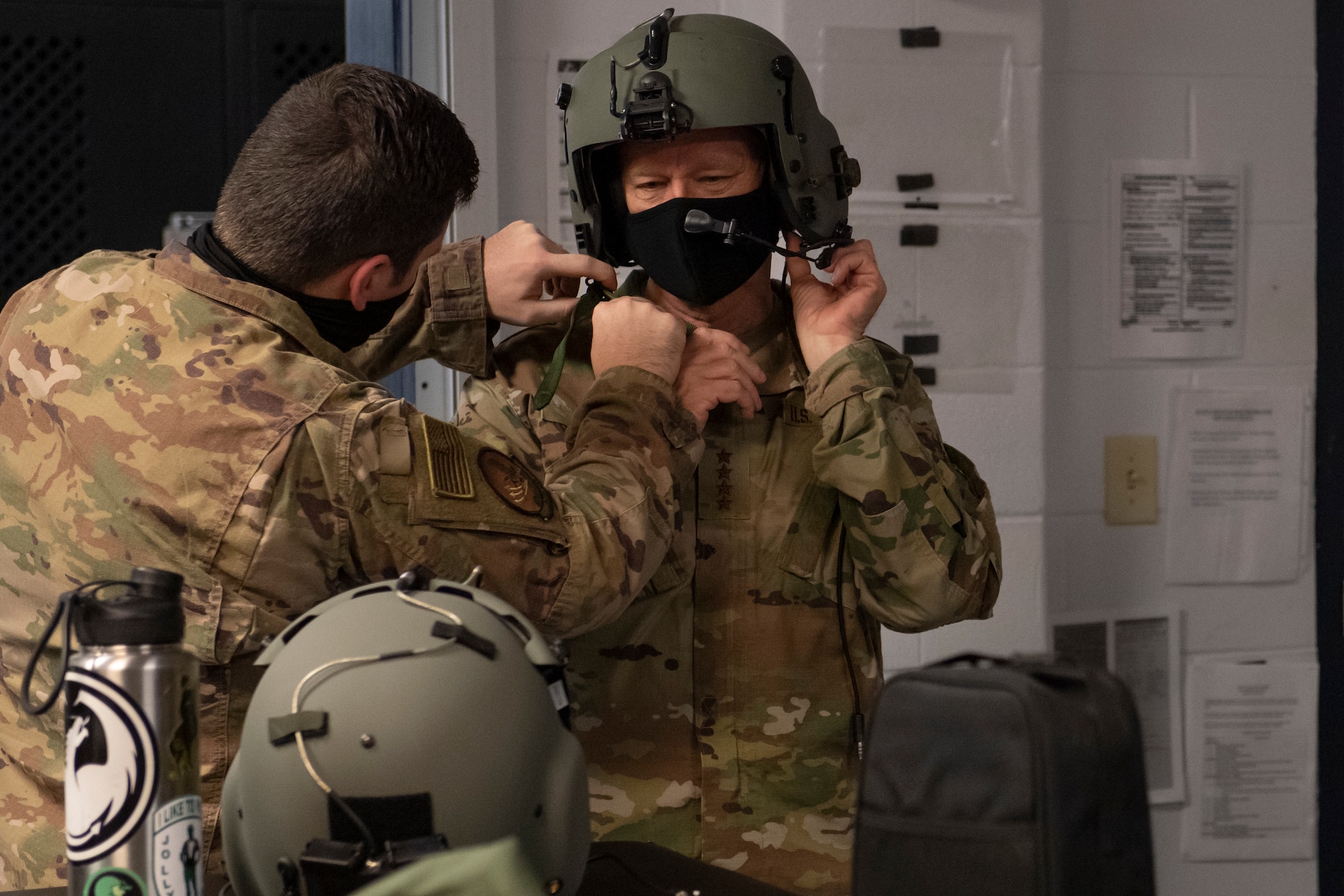 A photo of an Airman helping another Airman put a helmet on.