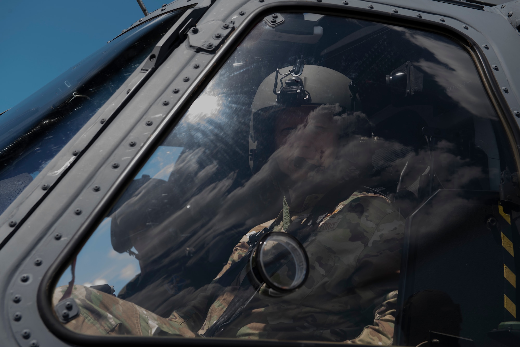 A photo of two Airmen siting in the cockpit of a helicopter.