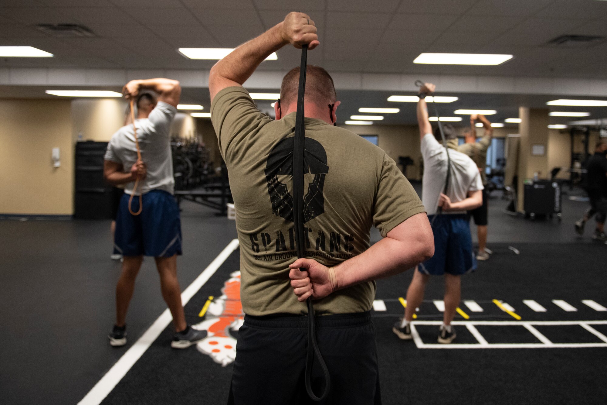 A photo of Chief Master Sgt. Wade using an exercise band stretched behind his back.