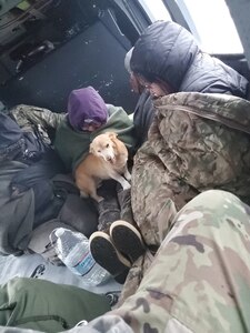 Four people and their dog warm up under blankets in a UH-60L Black Hawk helicopter from 1st Battalion, 207th Aviation Regiment, Alaska Army National Guard, after the helicopter aircrew rescued them on the Kuskokwim River in western Alaska May 10, 2021. The aircrew rescued the group after they became stuck on the river between Bethel and Kwethluk because of ice blocking their egress.