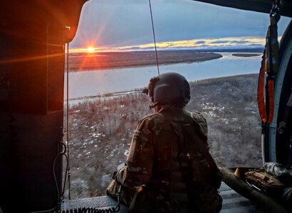 Sgt. Rosalind Stromberg, a crew chief from 1st Battalion, 207th Aviation Regiment, Alaska Army National Guard, looks over the Kuskokwim River from the door of a UH-60L Black Hawk helicopter during a rescue mission May 10, 2021. The helicopter aircrew rescued four people and their dog from their boat on the river after they became stuck between Bethel and Kwethluk because of ice.