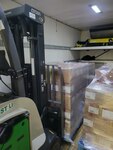 A forklift truck holds a pallet of material in a refrigerated space.
