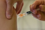 A needle containing flu vaccine is injected into an arm.