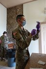 Man in uniform with a syringe in a bottle, removing vaccine.