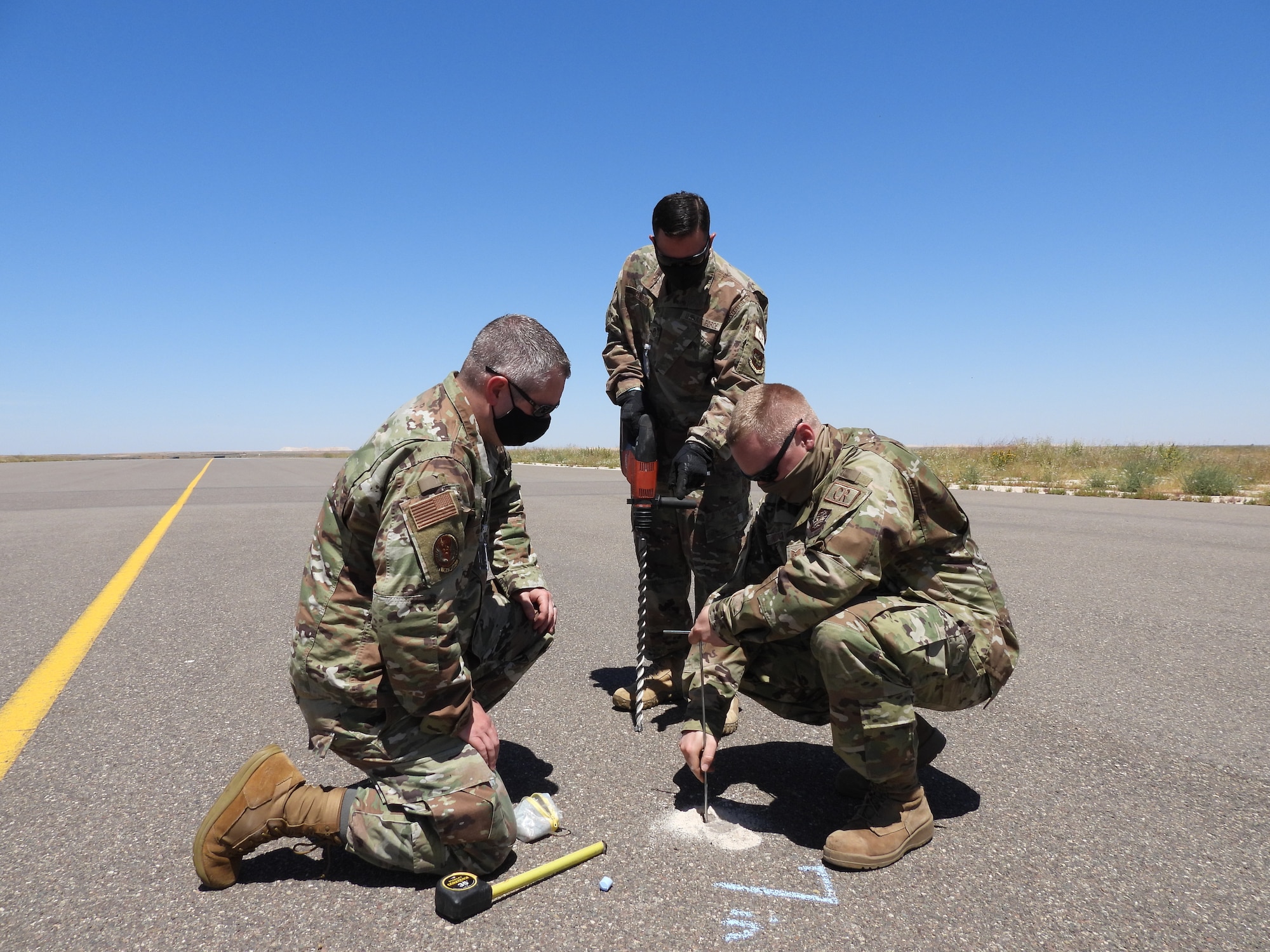 Tech. Sgt. William Russell, 818th Mobility Support Advisory Squadron air advisor, left, Master Sgt. John Vaccaro, 621st Contingency Response Squadron fuels technician, middle, and Tech. Sgt. Christopher Anderson, 621st Contingency Response Support Squadron civil engineer, right, measure the depth of pavement by drilling holes in a taxiway at Ben Guerir Air Base, Morocco, April 18, 2021. The members, assigned to an airfield survey team, deployed at the request of Air Mobility Command to conduct five airfield surveys across the Kingdom of Morocco ahead of African Lion 21, U.S. Africa Command’s largest exercise, scheduled to take place in Morocco, June 7-18. (courtesy photo)