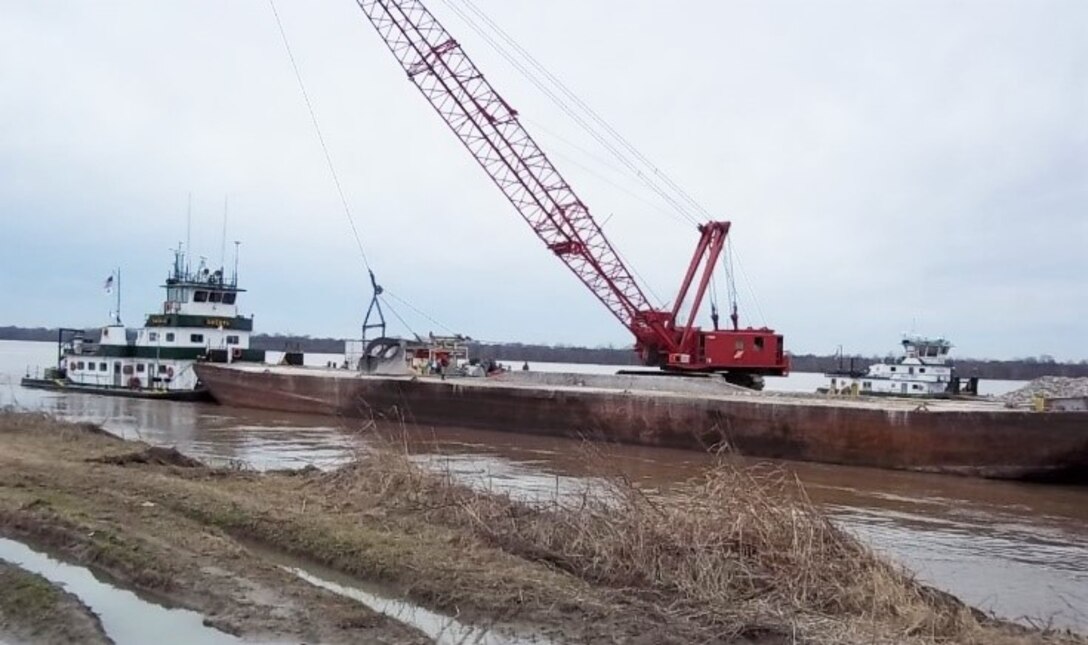 A progress photo of the Forked Deer Hard Points construction project. The construction for the task order awarded was completed on the current River Repairs IDIQ Contract to Midwest Construction Company (Luhr Brothers as a sub-contractor) for $614,600. The scope of work included placing 25,600 tons of 250-pound riprap stone on the river training structures of the Mississippi River. These repairs to the navigation channel were necessary to restore the existing hardpoints and to protect eroding and over-steepened banks between and behind the structures.