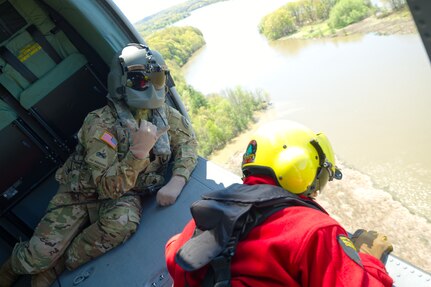 New York Army National Guard Staff Sgt. Jake Pratt, a UH-60 Black Hawk crew chief assigned to the 2rd Battalion, 142nd Aviation, and a New York State Department of Environmental Conservation forest ranger prepare to deploy water during helicopter firefighting training over the Mohawk River in Colonie, New York, May 6, 2021. Aircrews based at the Albany International Airport in Latham, New York, trained with aviators from the Connecticut Army National Guard and forest rangers in preparation for the summer wildfire season.