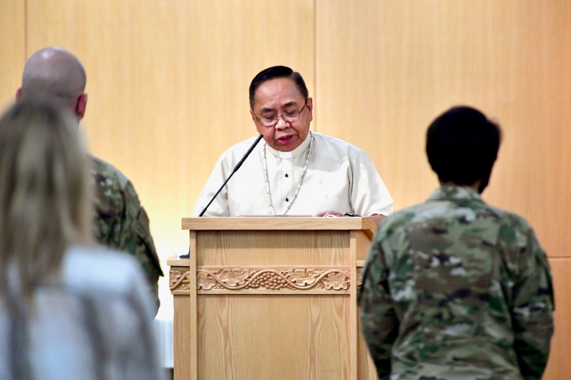 Father Max Ohana speaking from behind a podium.