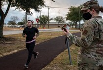 Airman times trainee as he passes finishing point on track.