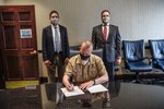 Capt. Todd Hutchison signs a Cooperative Research and Development Agreement (CRADA) between Naval Surface Warfare Center, Carderock Division (NSWCCD) and Thermal Compaction Group (TCG) on April 29, 2021. Behind Hutchison is Patrick Long, Technical Area Lead for Solid Waste in the Environmental Engineering, Science and Technology (Code 633), and Peter Mech, a representative from Naval Sea Systems Command’s program office for Ship Integrity and Performance Engineering (Solid Waste and Hazardous Material Management) (NAVSEA 05P5).