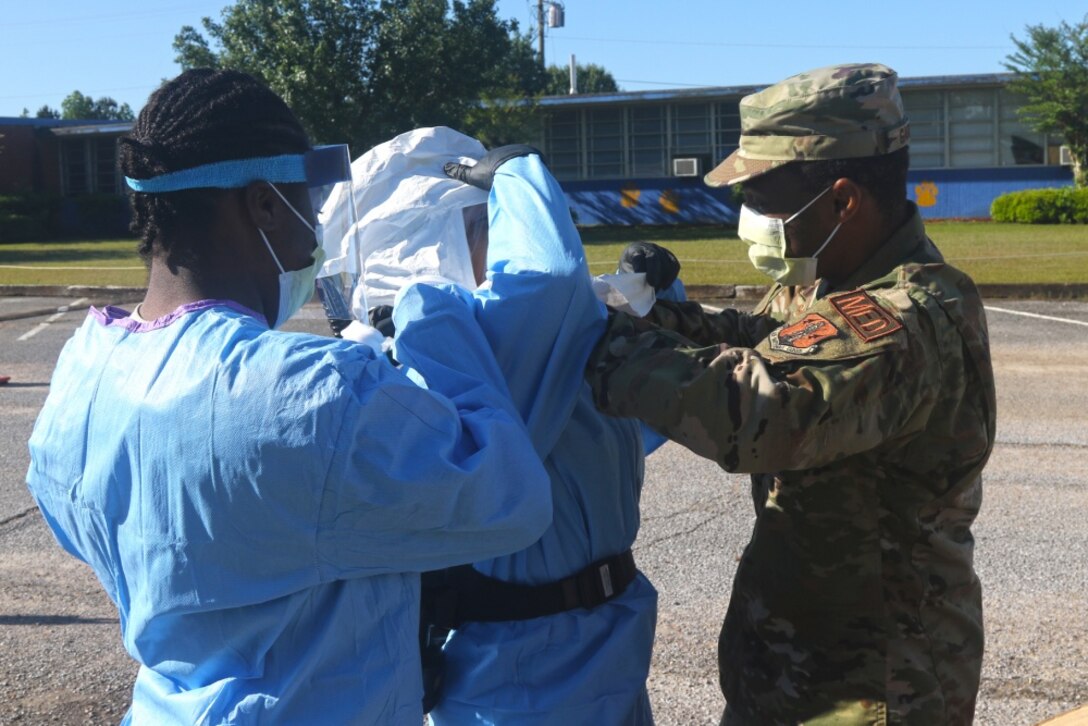 Airmen assigned to the 186th Air Refueling Wing, Mississippi Air National Guard, help U.S. Air Force Tech. Sgt. Adriana Campbell-Page, COVID-19 test administrator, put on her personal protection equipment at a mobile testing site in De Kalb, Miss., Apr. 24, 2020. The DLA Troop Support Medical PPE team earned Team of the Year Award for their 2020 COVID-19 support, and DLA Troop Support employees Linnette De La Cruz and John Trunzo also earned Employee and Supervisor of the Year Awards, respectively, for their 2020 mission support.