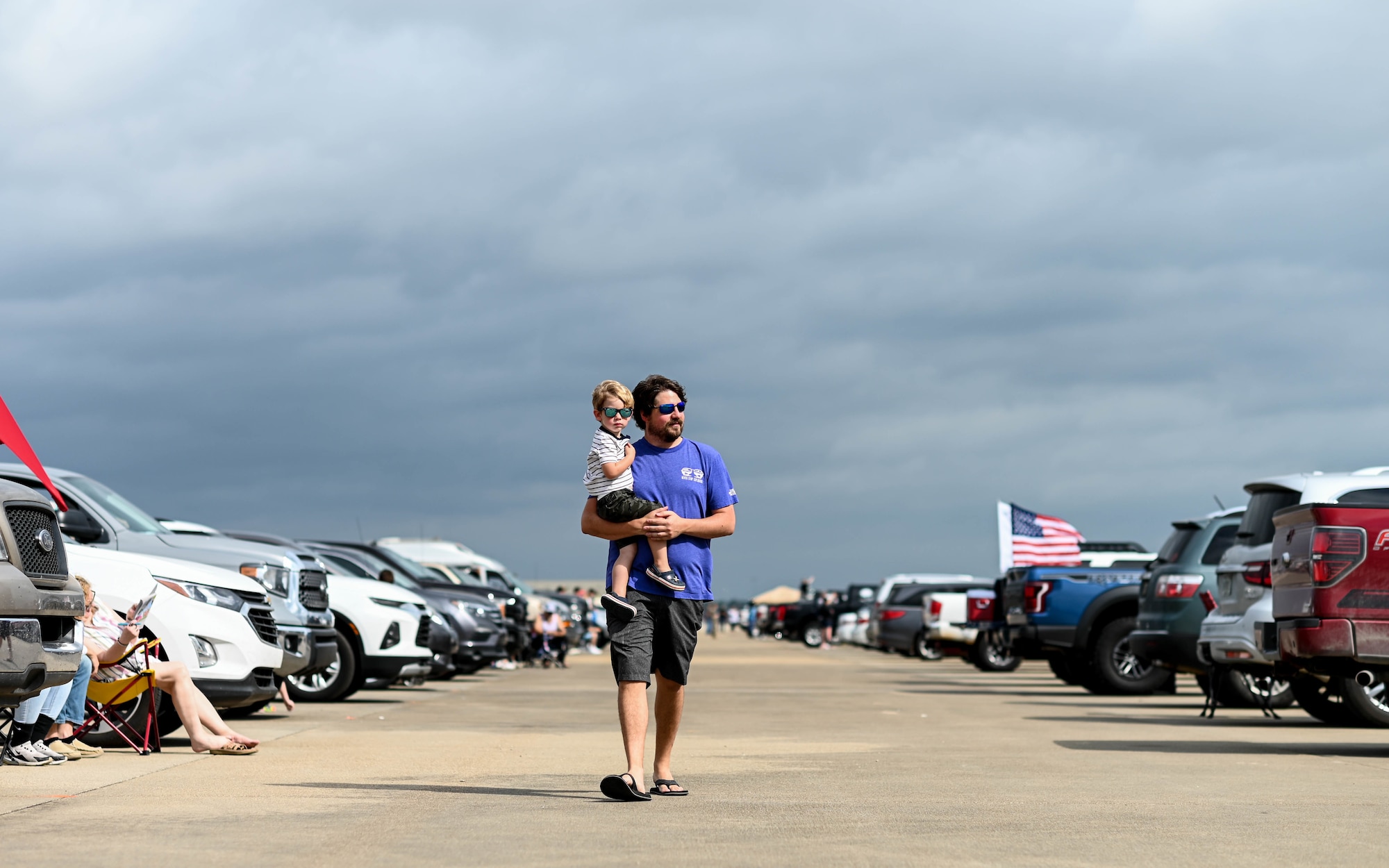 A father carries his son down the flightline at the 2021 Defenders of Liberty Air & Space Show at Barksdale Air Force Base, Louisiana, May 9, 2021. Barksdale Air Force Base premiered its first ever drive-in show to enforce social-distancing standards. (U.S. Air Force photo by Senior Airman Christina Graves)