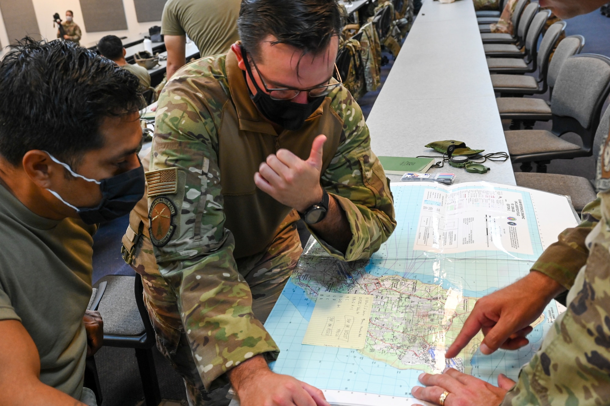 A student from the 644th Combat Communications Squadron gives a thumps up after successfully plotting coordinates using a map during their classroom portion of training on North West Field, Guam, April 9, 2021. Students took part in exercise Dragon Forge a combat skills training course that prepares participants to deploy to austere locations. (U.S. Air Force photo by Tech. Sgt. Esteban Esquivel)