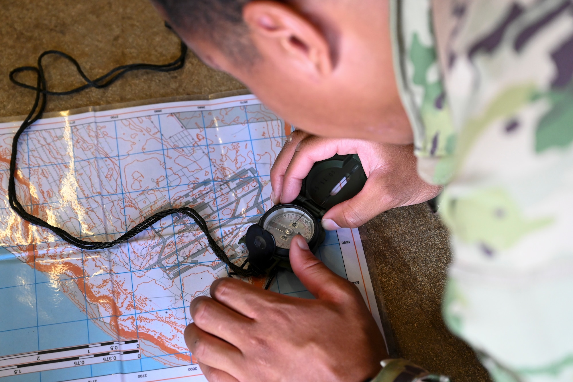 U.S. Air Force 1st Lt. Jarrod Hardrick, 36th Contingency Response Support Squadron training and readiness flight commander, uses a compass to plot his route during land navigation skills training on North West Field, Guam, April 13, 2021. Students spent three weeks learning various skills to help them in combat and survival during exercise Dragon Forge. Exercise DF is a combat skills training course that prepares participants to deploy to austere locations. (U.S. Air Force photo by Tech. Sgt. Esteban Esquivel)