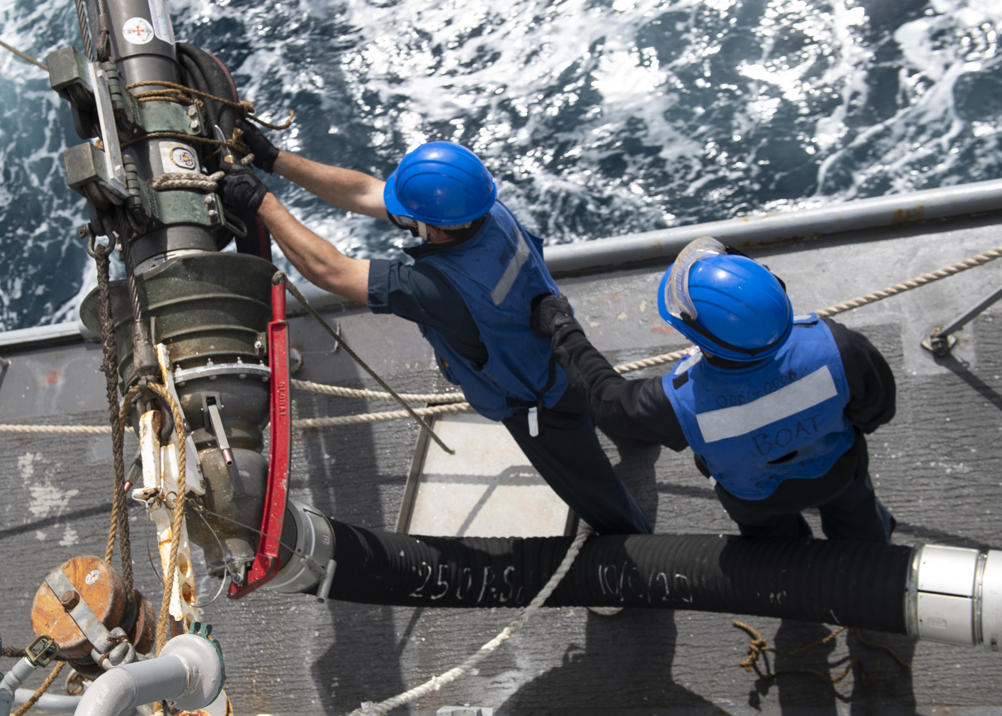 Sailors cut rigging line from a fueling probe aboard the Arleigh Burke-class guided-missile destroyer USS Rafael Peralta (DDG 115) during a vertical replenishment (VERTREP)