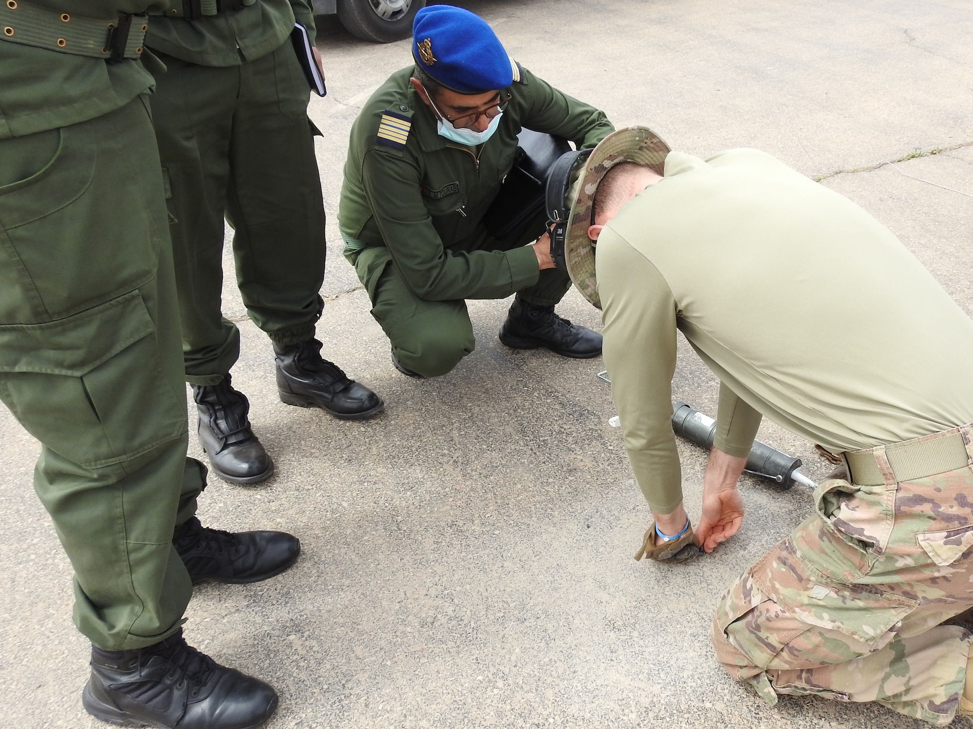 Col. Mohammed Tourabi, Royal Moroccan Air Force, left, observes as Capt. Jack Robinson, 821st Contingency Response Support Squadron airfield assessment team chief and civil engineer, right, seals the pavement test point at the Inezgane Airport, Morocco, April 24, 2021. After drilling into the pavement and performing the Dynamic Cone Penetrometer structural test the airfield survey team seals the pavement with silicone to minimize the impact of the test on the lifecycle of the pavement. (courtesy photo)