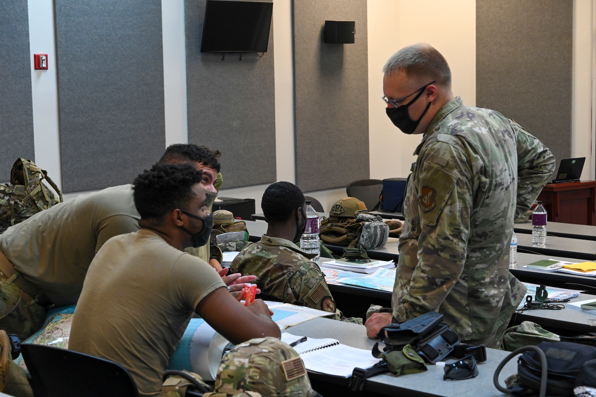 An instructor for exercise Dragon Forge assists students attempting to plot coordinates using a map during their classroom portion of training on North West Field, Guam, April 9, 2021. Exercise DF is a combat skills training course that prepares participants to deploy to austere locations. (U.S. Air Force photo by Tech. Sgt. Esteban Esquivel)