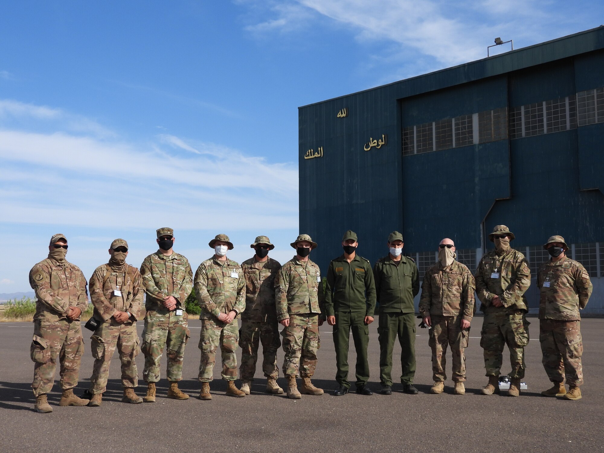 Airmen with the 621st Contingency Response Wing airfield survey team and members of the Royal Moroccan Air Force pose for a group photo in front of an aircraft hangar at Ben Guerir Air Base, Morocco, April 21, 2021. The Royal Moroccan Air Force motto “God, Country, King” can be seen written in Arabic on the hangar. Missions like this allow Devil Raiders to strengthen relationships with partner nations. (courtesy photo)