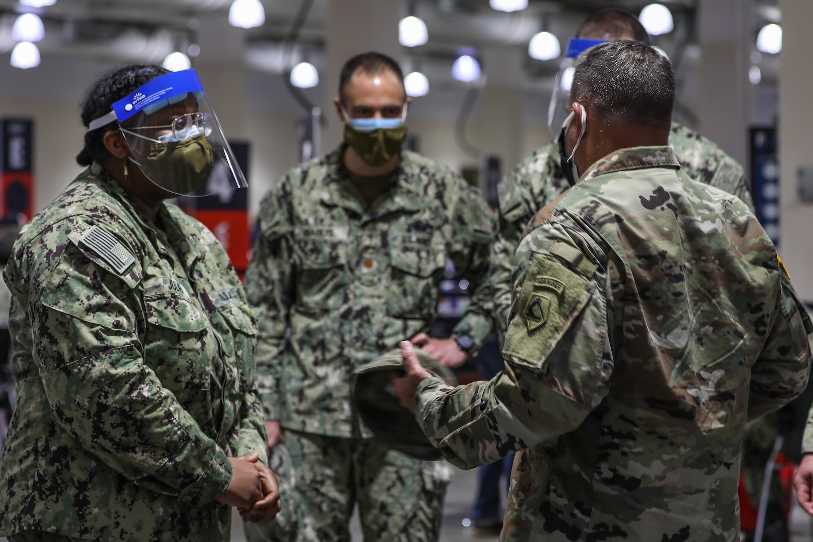 U.S. Navy Hospitalman Kristie Julien, left, assigned to Naval Medical Center Portsmouth, Virginia, receives a coin from U.S. Army Brig. Gen. Ronald Cupples, right, the assistant adjutant general for the Massachusetts National Guard, for being the Vaccinator of the Week, April 12-18, and vaccinating approximately 425 local community members, at the Community Vaccination Center at the Hynes Convention Center in Boston, April 30, 2021.