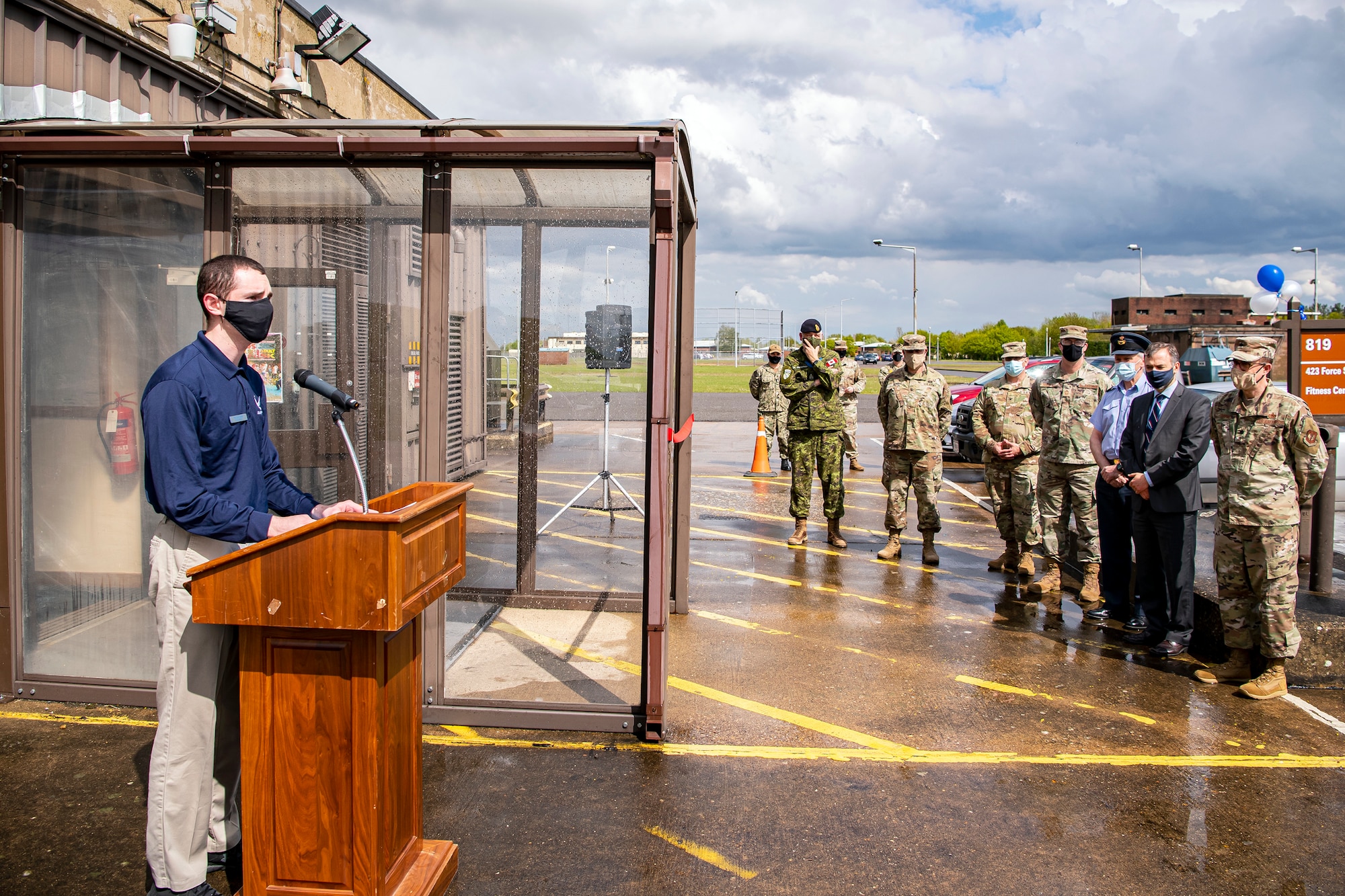 U.S. Air Force Staff Sgt. Kyle Klein, left, 423rd Force Support Squadron fitness specialist, speaks during a ribbon cutting ceremony at RAF Molesworth, England, May 11, 2021. Leadership from RAF Alconbury and RAF Molesworth attended the ceremony to celebrate the reopening of the base gym after months of refurbishing and renovations. (U.S. Air Force photo by Senior Airman Eugene Oliver)