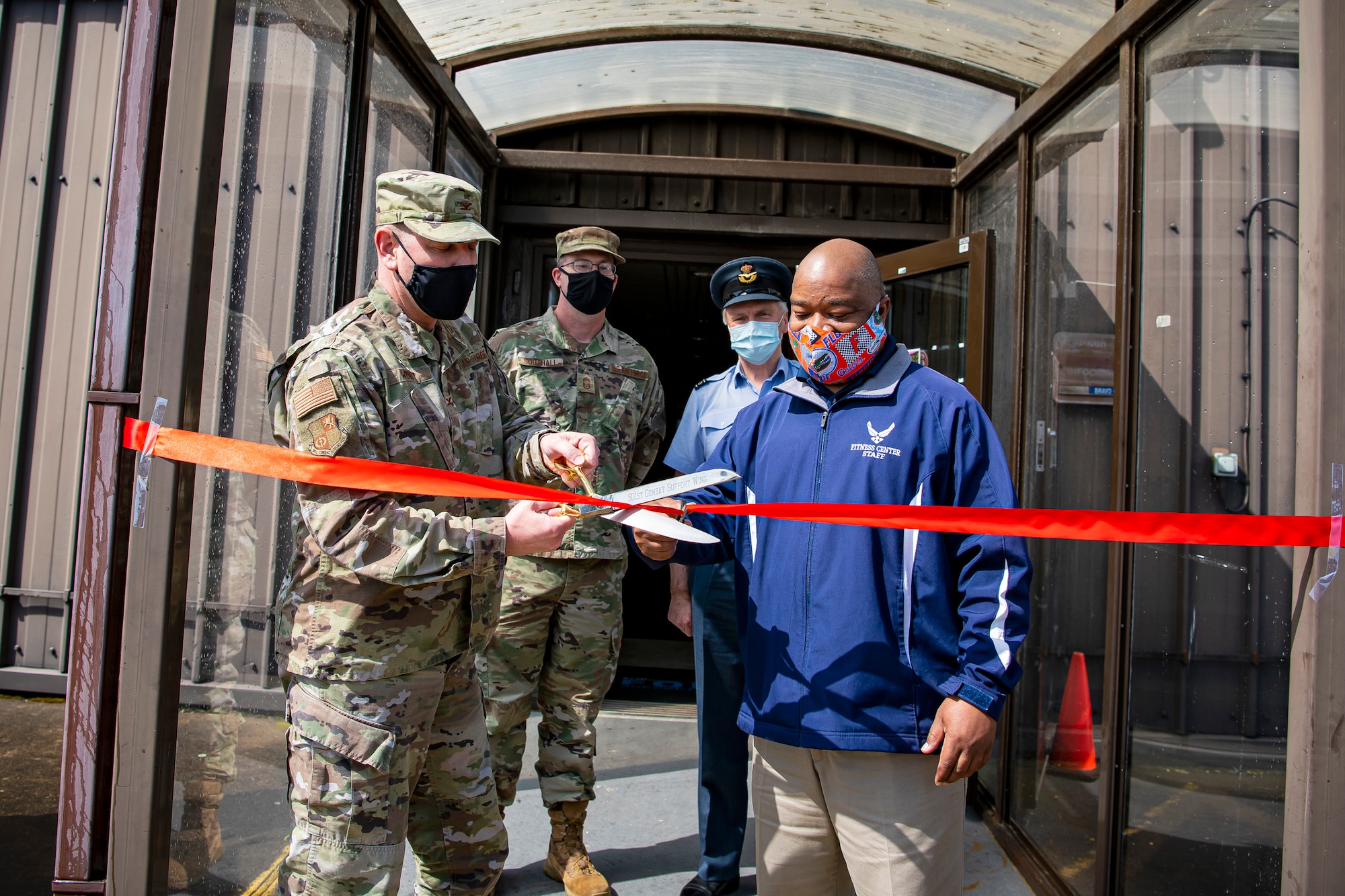 U.S. Air Force Col. Kurt Wendt, left, 501st Combat Support Wing commander, and Marcel Gibson, right, 423rd Force Support Squadron director of fitness and sports, cut the ribbon for the renovated fitness center at RAF Molesworth, England, May 11, 2021. Leadership from RAF Alconbury and RAF Molesworth attended the ceremony to celebrate the reopening of the base gym after months of refurbishing and renovations. (U.S. Air Force photo by Senior Airman Eugene Oliver)