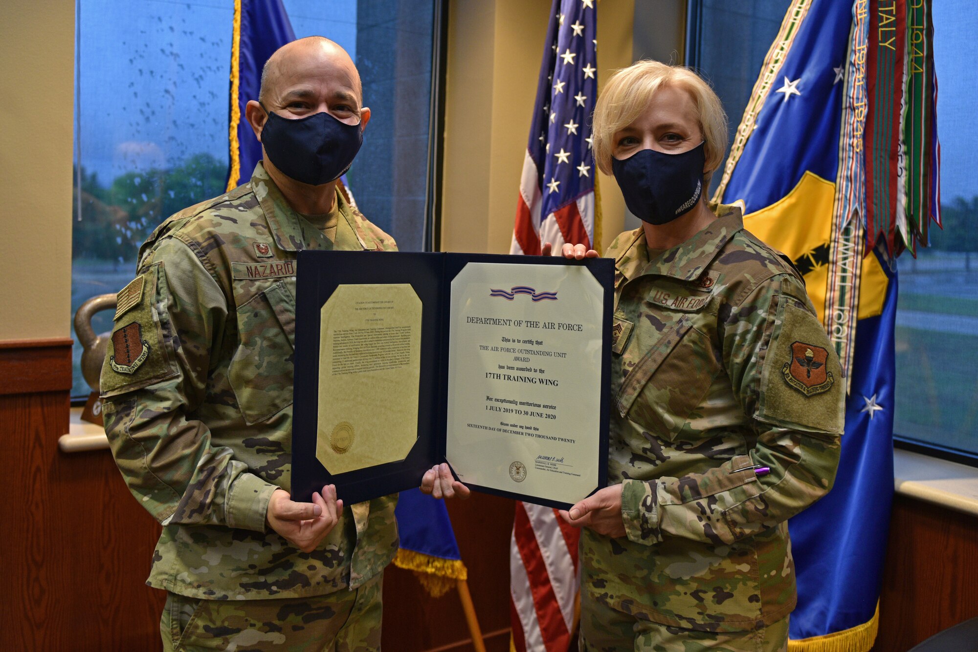 U.S. Air Force Col. Andres Nazario, 17th Training Wing commander, stands with Chief Master Sgt. Casy Boomershine, 17th TRW command chief, displaying the 2020 Air Force Outstanding Unit Award, in the Norma Brown Building on Goodfellow Air Force Base, Texas, May 11, 2021. The Outstanding Unit Award is awarded by the Secretary of the Air Force to units that have distinguished themselves through meritorious service or outstanding achievement. (U.S. Air Force photo by Senior Airman Ashley Thrash)