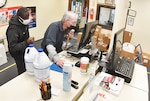 Base Supply Center employee Steve McGuire scans office supplies at the register while being aided by fellow employee Collin Knight April 14 at the Fort Lee AbilityOne Base Supply Center. A new Troop Support C&E AbilityOne Base Supply Center Tailored Logistics Support Program allows 16 nonprofit agencies under the NIB umbrella to compete for large purchase requests from customers throughout their 150 storefront shops on military installations and in federal buildings. (photo by T. Anthony Bell).