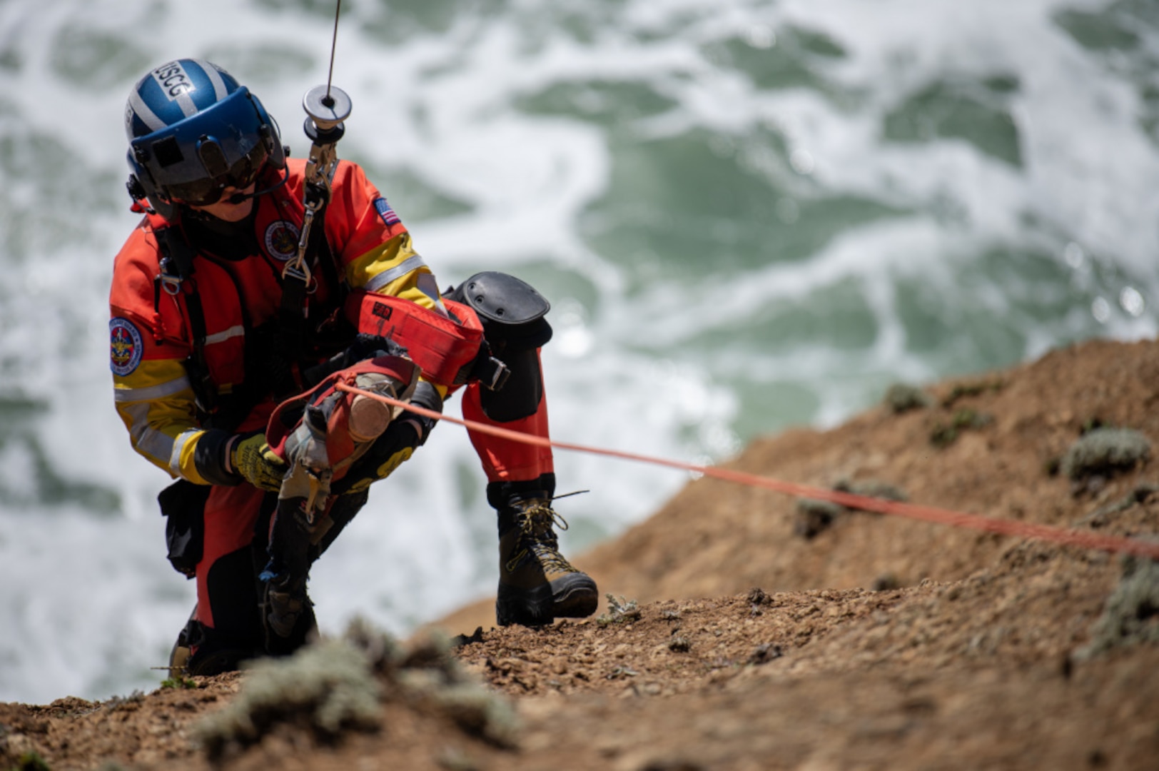 Petty Officer 2nd Class Noah Colburn, an aviation survival technician stationed at Air Station San Francisco, tends to a simulated individual during cliff rescue training Pacifica, Calif., March 30, 2021. Cliff rescue training is one of many exercise crews use to stay proficient in all mission capabilities. (U.S. Coast Guard Photo by Petty Officer 3rd Class Taylor Bacon)