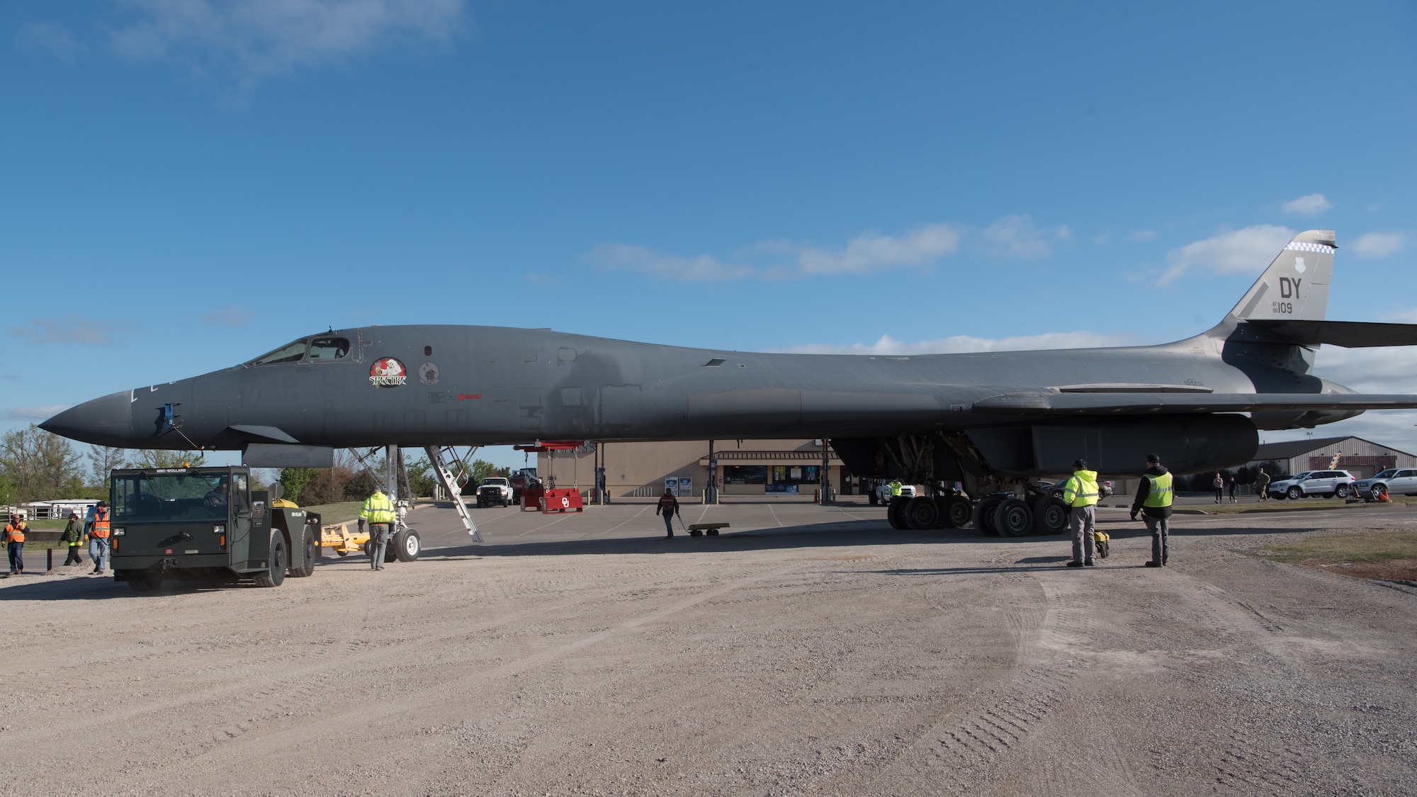 B-1B aircraft being towed off street into gravel road.