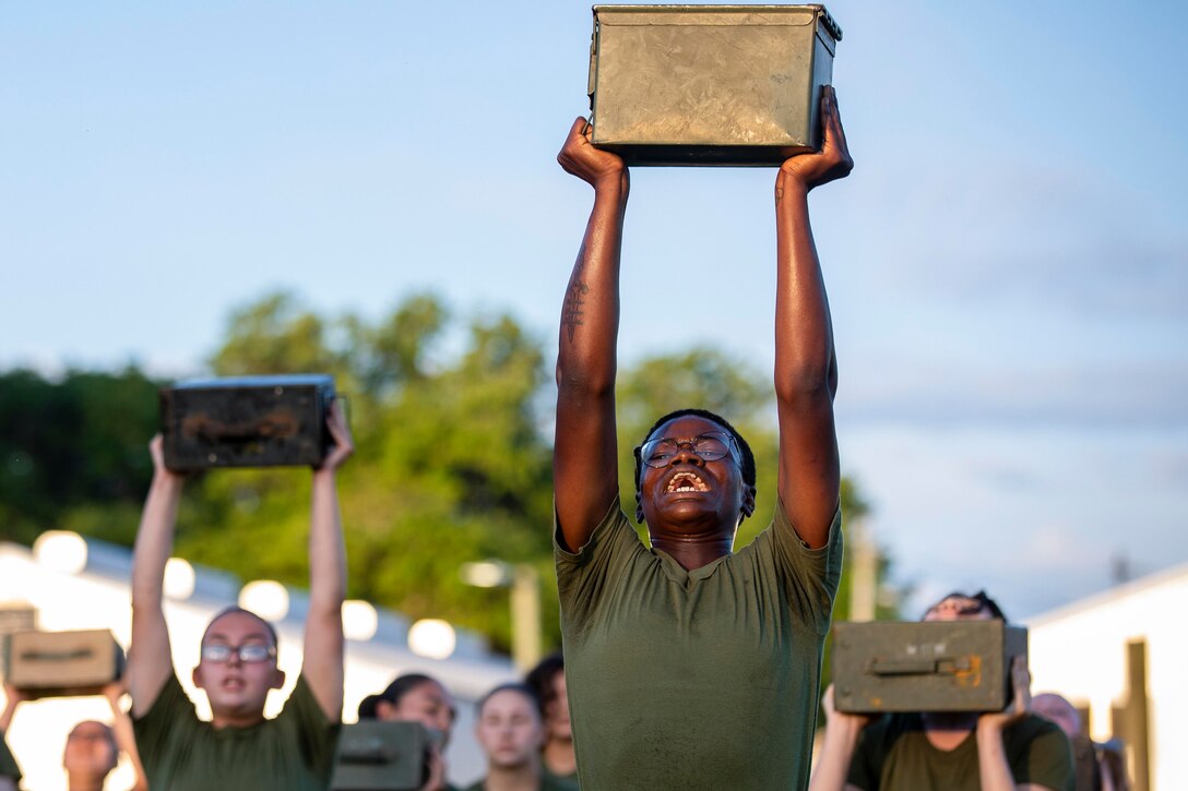 Marine Corps recruits lift ammo cans above their heads.