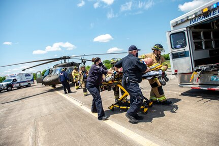 Firefighters from the Tulsa, Oklahoma Fire Department and EMSA personnel transport a simulated casualty played by and Oklahoma Army National Guard Citizen-Soldier from a mock helicopter crash at the Oklahoma Army National Guard's Army Aviation Support Facility 2 in Tulsa, Oklahoma, May 12, 2021. Pre-accident training prepares Army aviation units to respond to accidents ranging from slip and falls to mass casualty events. (Oklahoma National Guard photo by Anthony Jones)