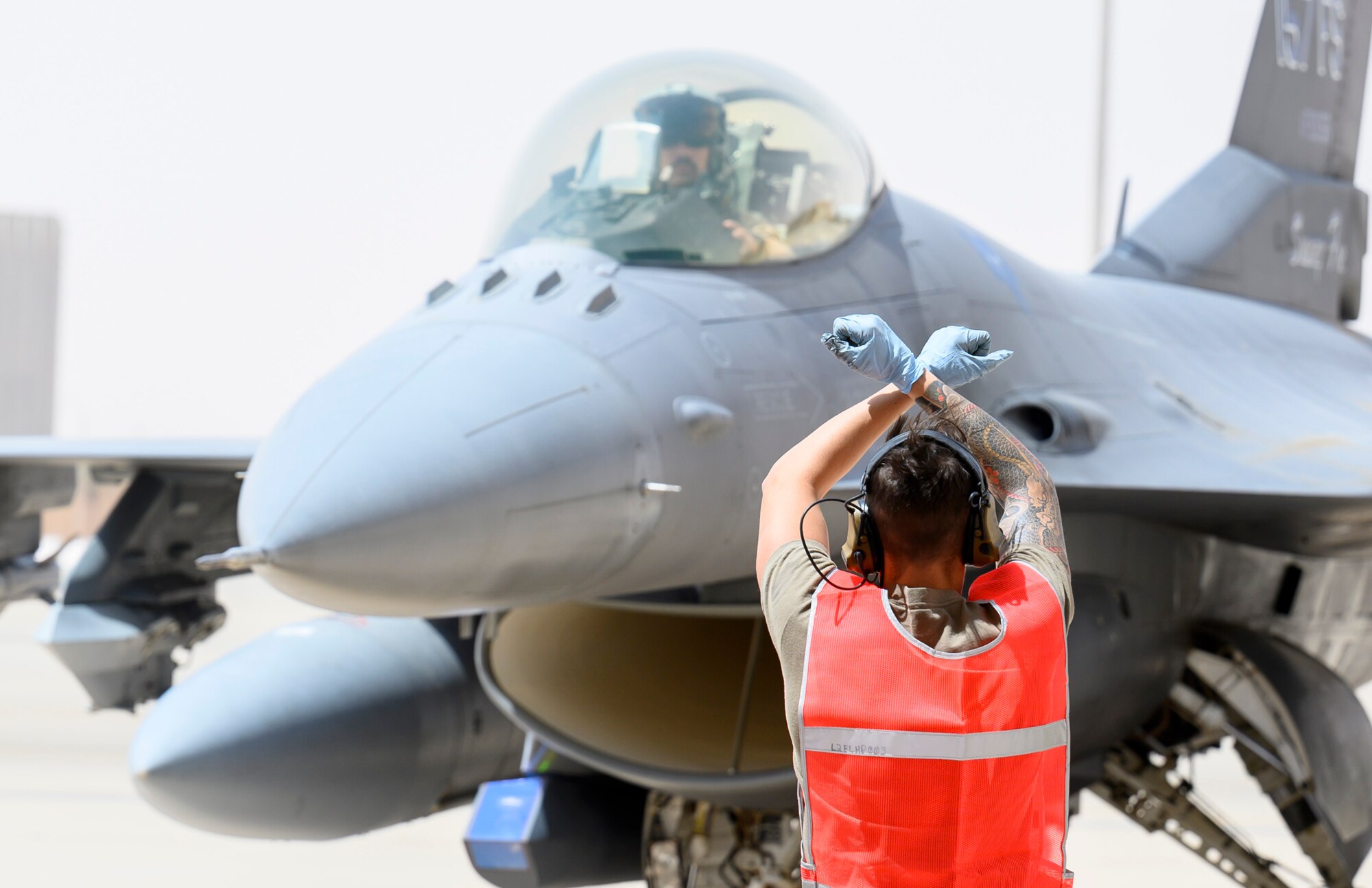 Senior Airman Shane Brennan, 379th Expeditionary Maintenance Squadron C-130 crew chief, motions to the pilot, 157th Expeditionary Fighter Squadron, to stop movement during “hot pit” training, Prince Sultan Air Base, Kingdom of Saudi Arabia, May 3, 2021. Hot pit refueling is where maintainers refuel an aircraft while the engine is still running, allowing the aircraft to safely and quickly return to flying. (U.S. Air Force Photo by Senior Airman Samuel Earick)