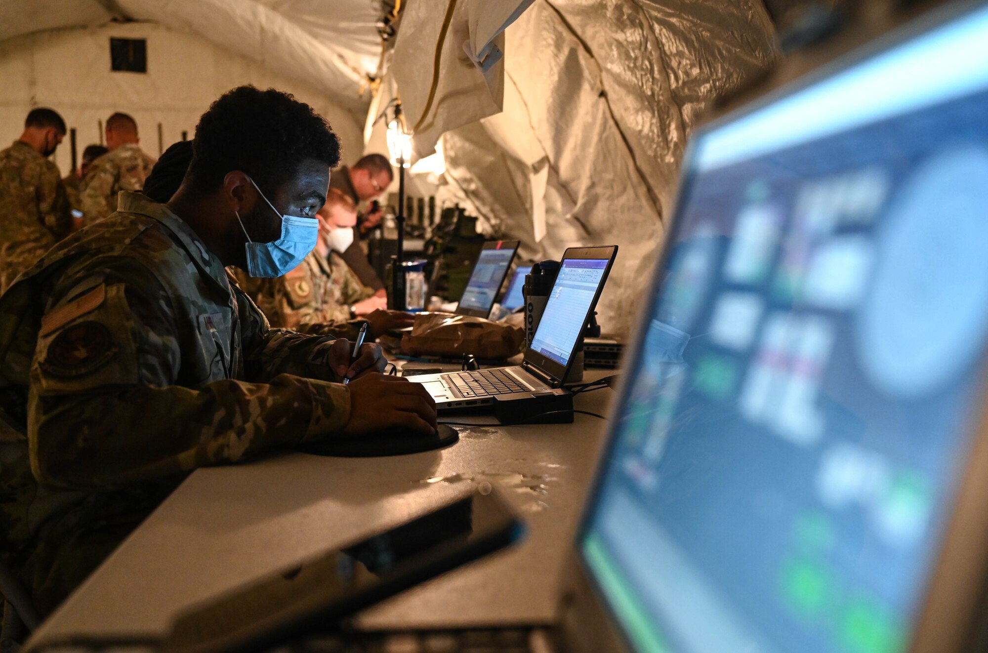 Airmen use laptops in a makeshift forward operating base during the Agile Flag 21-2 exercise at Naval Outlying Landing Field Choctaw, Fla., May 3, 2021. Air Combat Command developed the Agile Flag 21-2 experiment to create a lead wing, aligning squadrons from different locations under a single commander, enhancing their readiness as a team before deploying into a contested environment.