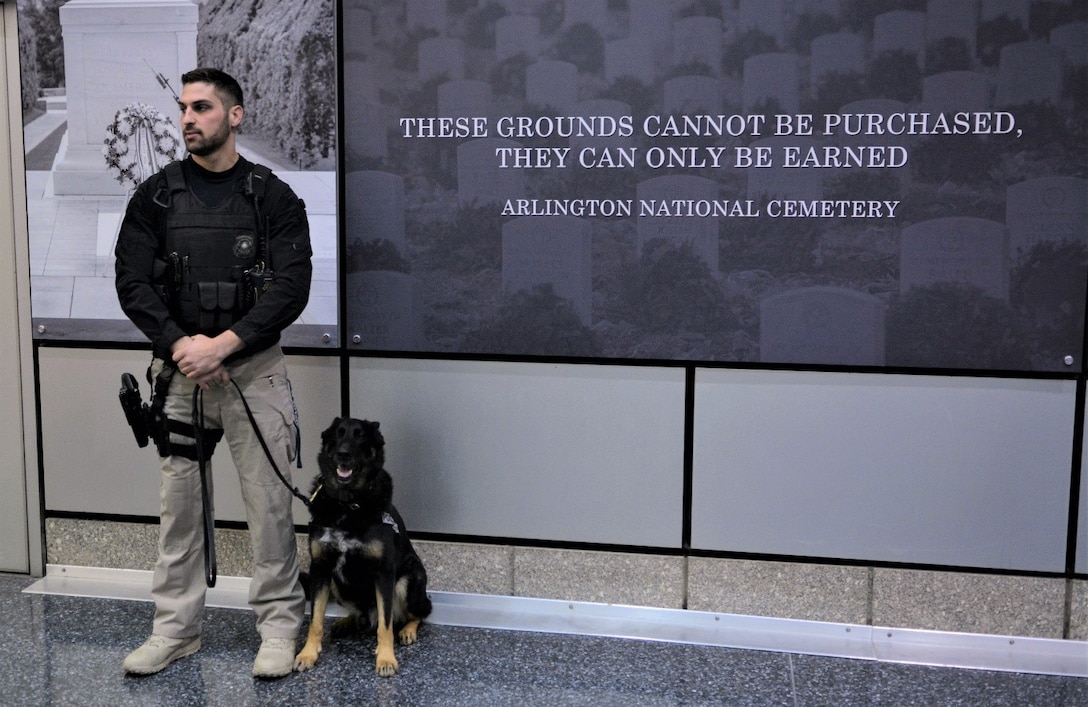 DIA Police Sgt. Josh DePasquale stands watch with Rex at DIA Headquarters during an event in 2019. (Photo by Ally Rogers, DIA Public Affairs)