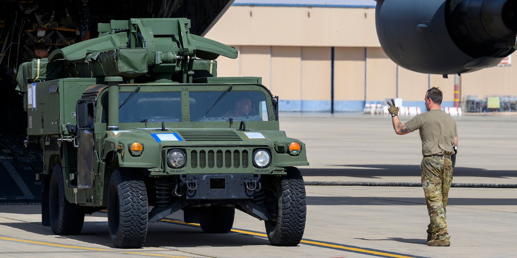 A member of the 378th Expeditionary Logistics Readiness Squadron Air Terminal Operations Center gives the go ahead to a HUMMWV after it was unloaded from a U.S. Air Force C-17 at Prince Sultan Air Base, Kingdom of Saudi Arabia, May 5, 2021. Personnel, aircraft, and supplies from Marine All Weather Fighter Attack Squadron 224, Marine Aircraft Group 31, deployed as part of a dynamic force employment to PSAB from Marine Corps Air Station Beaufort, South Carolina, to enhance U.S. Central Command’s ability to deter aggression and promote security and stability within the USCENTCOM area of responsibility. (U.S. Air Force photo by Senior Airman Samuel Earick)