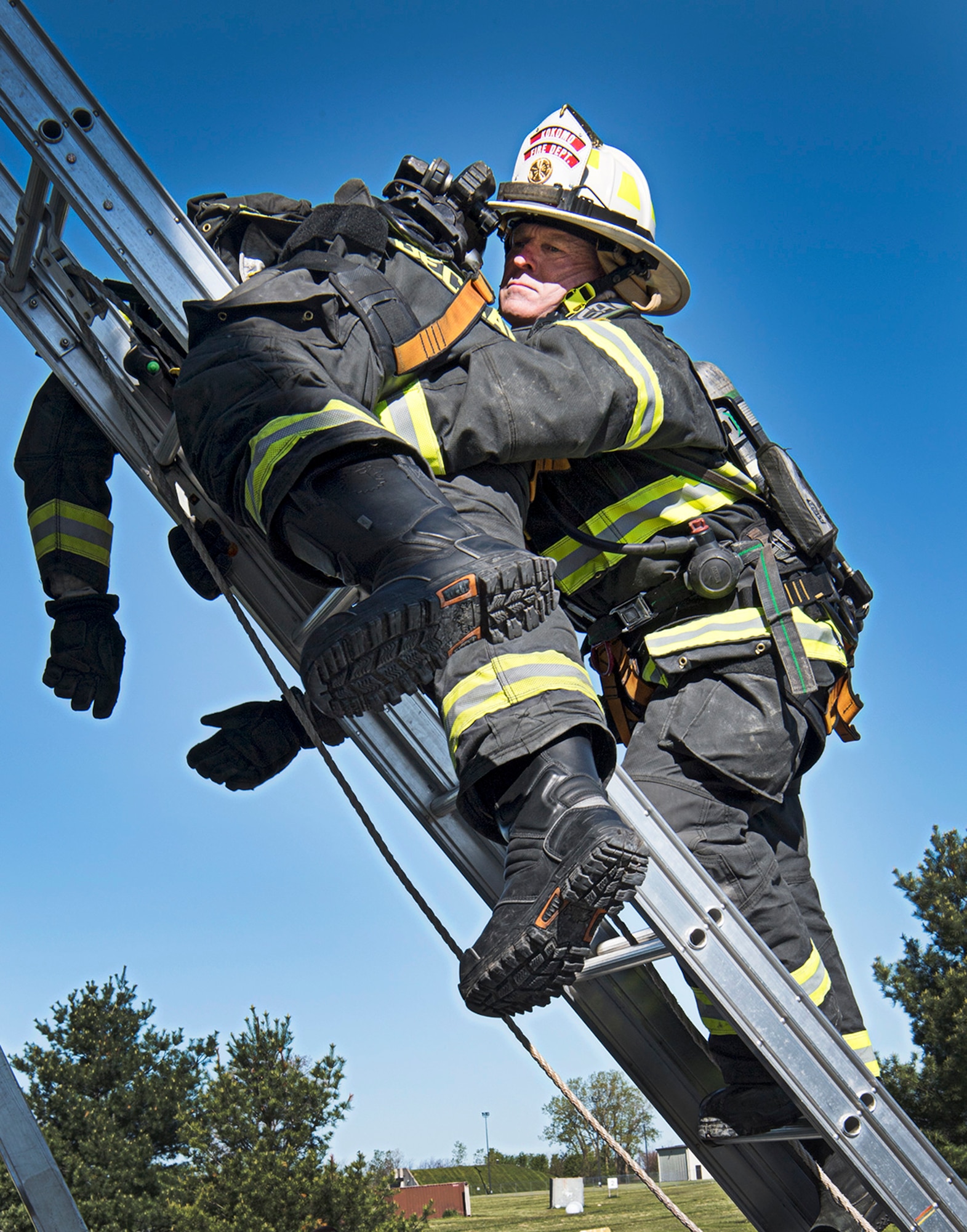 Chris Frazier, a fireman from the Kokomo City Fire Department, lowers Philip Deckard, also Kokomo FD, from a second story window during training at Grissom May 12, 2021. Military and civilian firefighters gathered at Grissom May 10-14 for a rescue and survival training course. (Air Force photo by Douglas Hays)