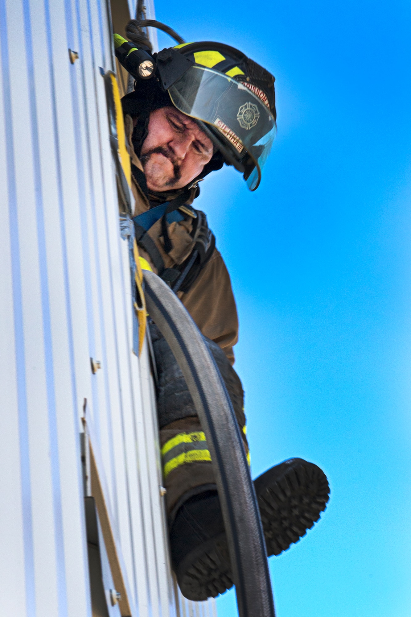 Francisco Sierra III, a firefighter with the Grissom Fire Department, egresses from a second-story window using a fire hose to escape a ‘burning structure’ during training here May 11, 2021. Firefighters from six different departments trained here May 10-14. (Air Force photo by Douglas Hays)
