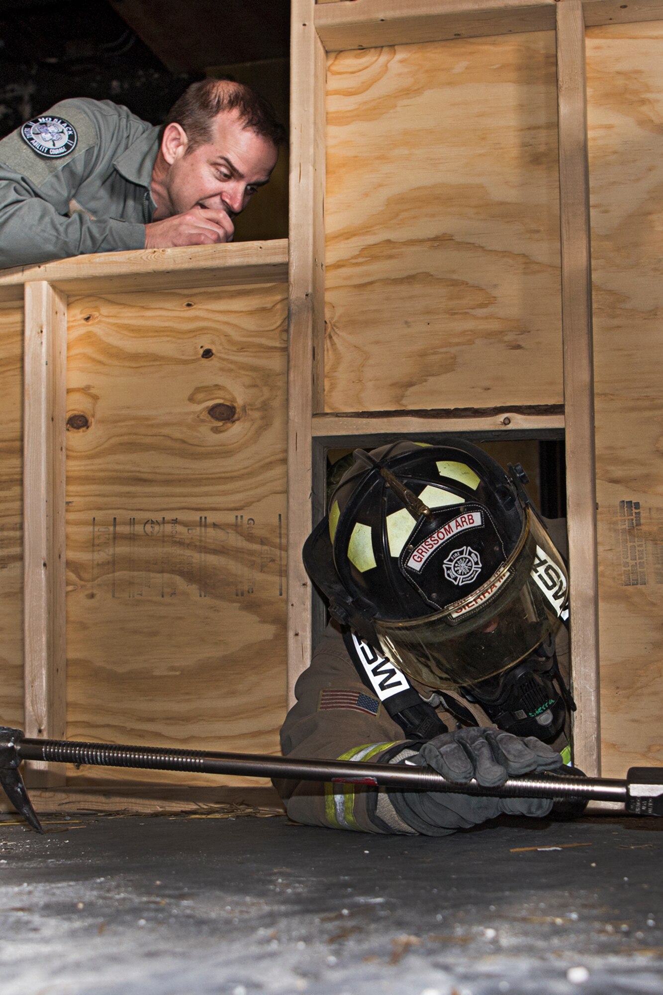 Tech. Sgt. Nicholas Behr, a firefighter from the 445th Civil Engineer Squadron at Wright-Patterson AFB, Ohio, encourages Francisco Sierra III, a firefighter with the Grissom Fire Department as he makes his way through a confined space opening at Grissom May 11, 2021. Firefighters from six different departments trained here May 10-14. (Air Force photo by Douglas Hays)