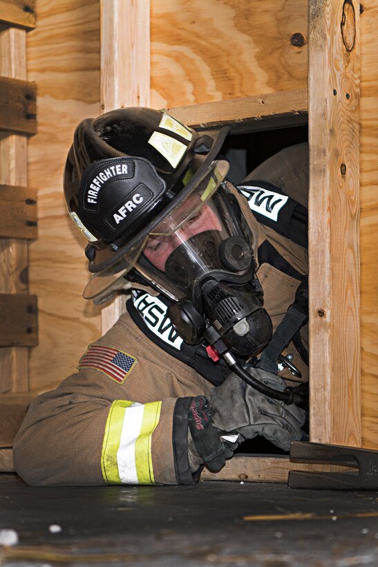 Staff Sgt. Braden Hood, 434th Civil Engineer Squadron fire protection specialist, squeezes through a confined space opening at Grissom May 11, 2021. Firefighters from six different departments trained here May 10-14, 2021. (Air Force photo by Douglas Hays)