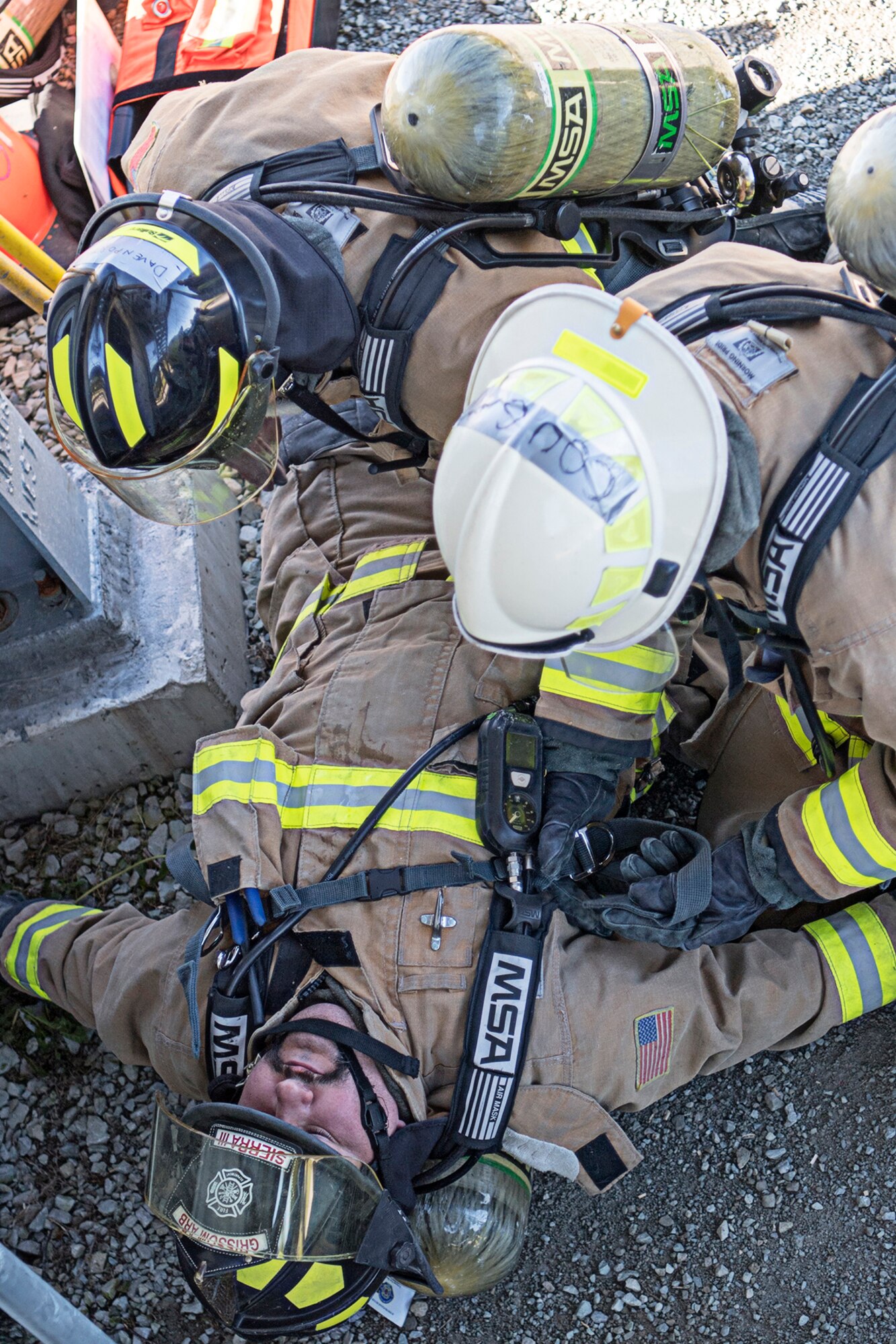 Nicholas Sierra III, bottom,  is evaluated and prepared to be carried up two flights of stairs by Senior Airmen Luke Limecooly, right, and Staff Sgt. Andrew Davenport. Sierra is a civilian firefighter at Grissom, and Limecooly and Davenport are both military firefighters with the 434th Civil Engineer Squadron. (Air Force photo by Douglas Hays)