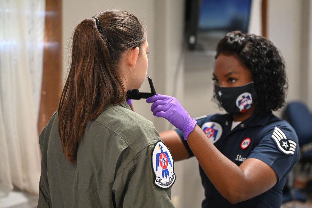 An airman uses a tool to measure a woman's head.