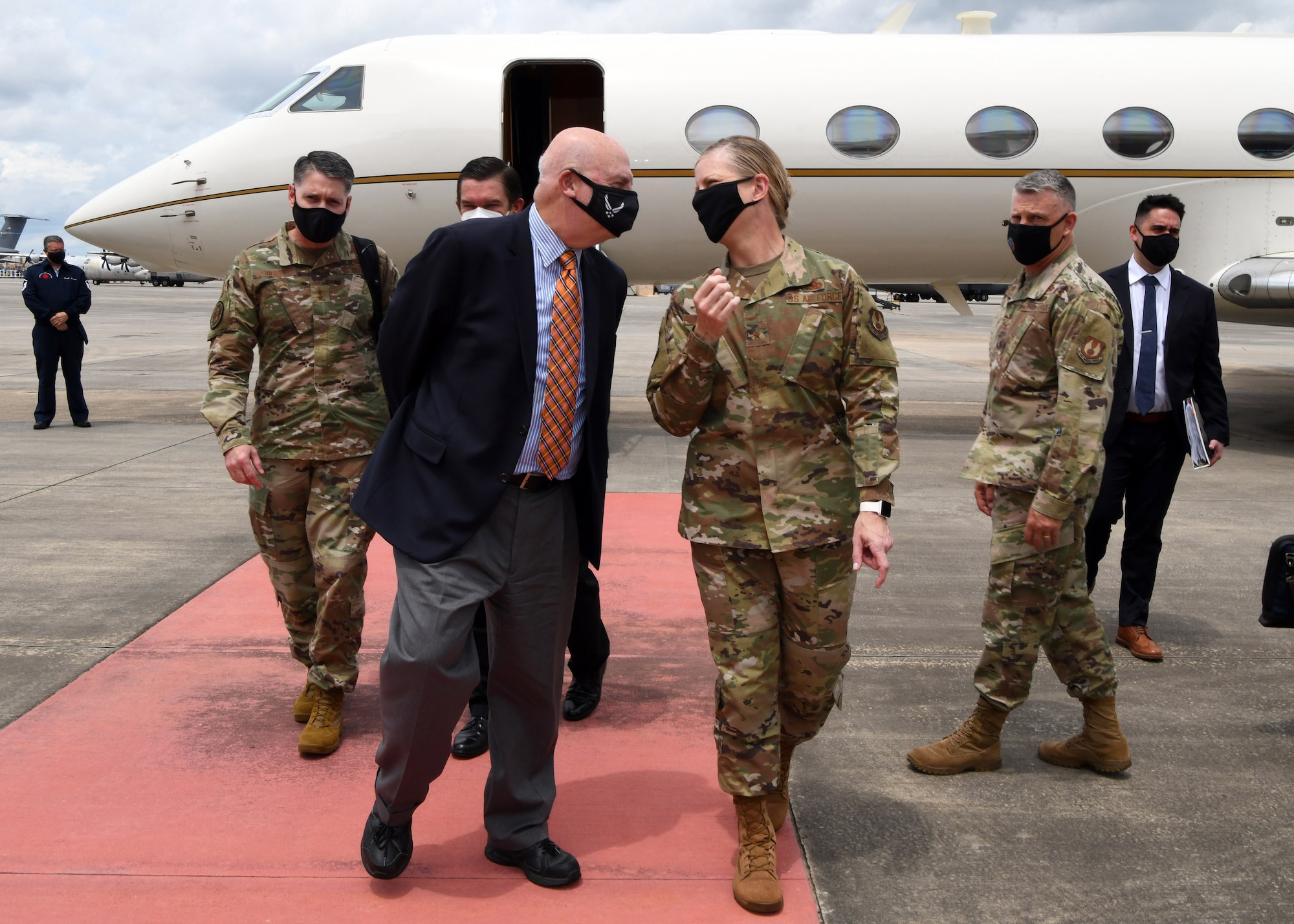 Photo shows group of people speaking and walking away from an aircraft.