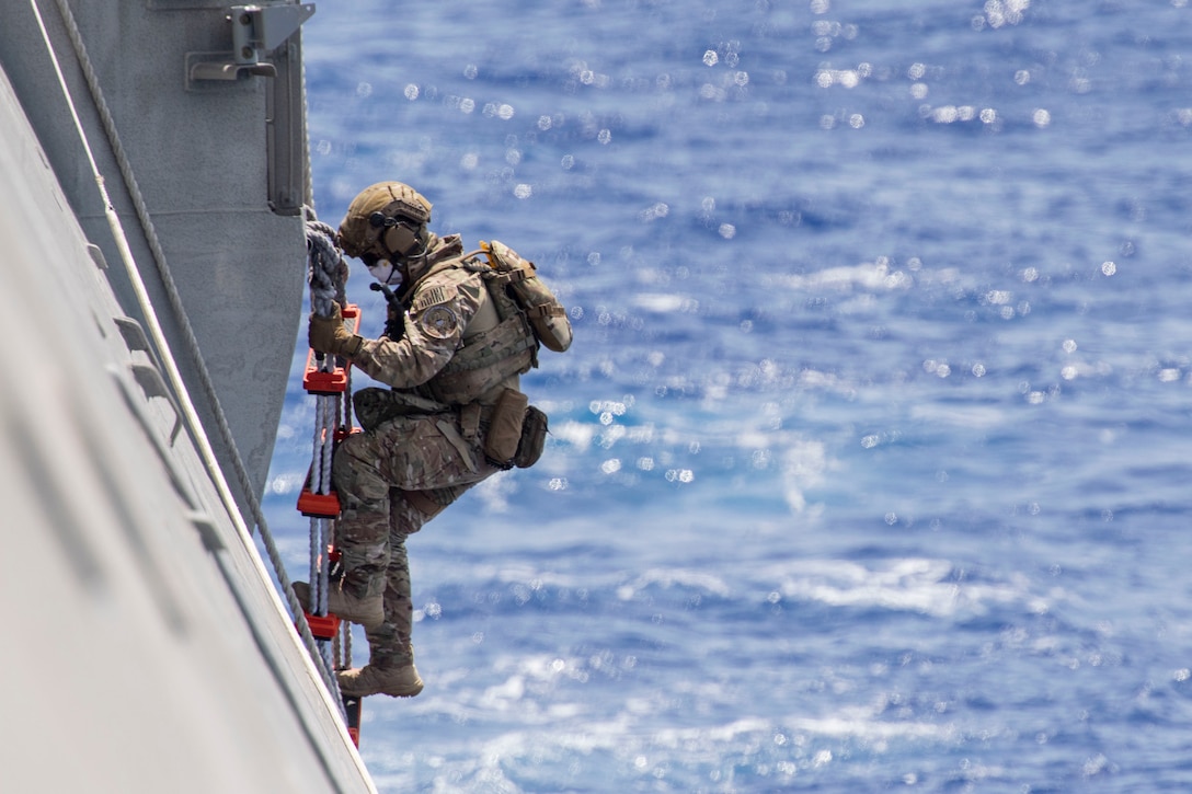 A Coast Guardsman descends a ladder on a ship.
