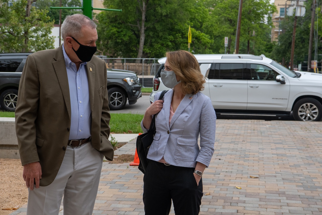 A man and woman stand outside and talk.