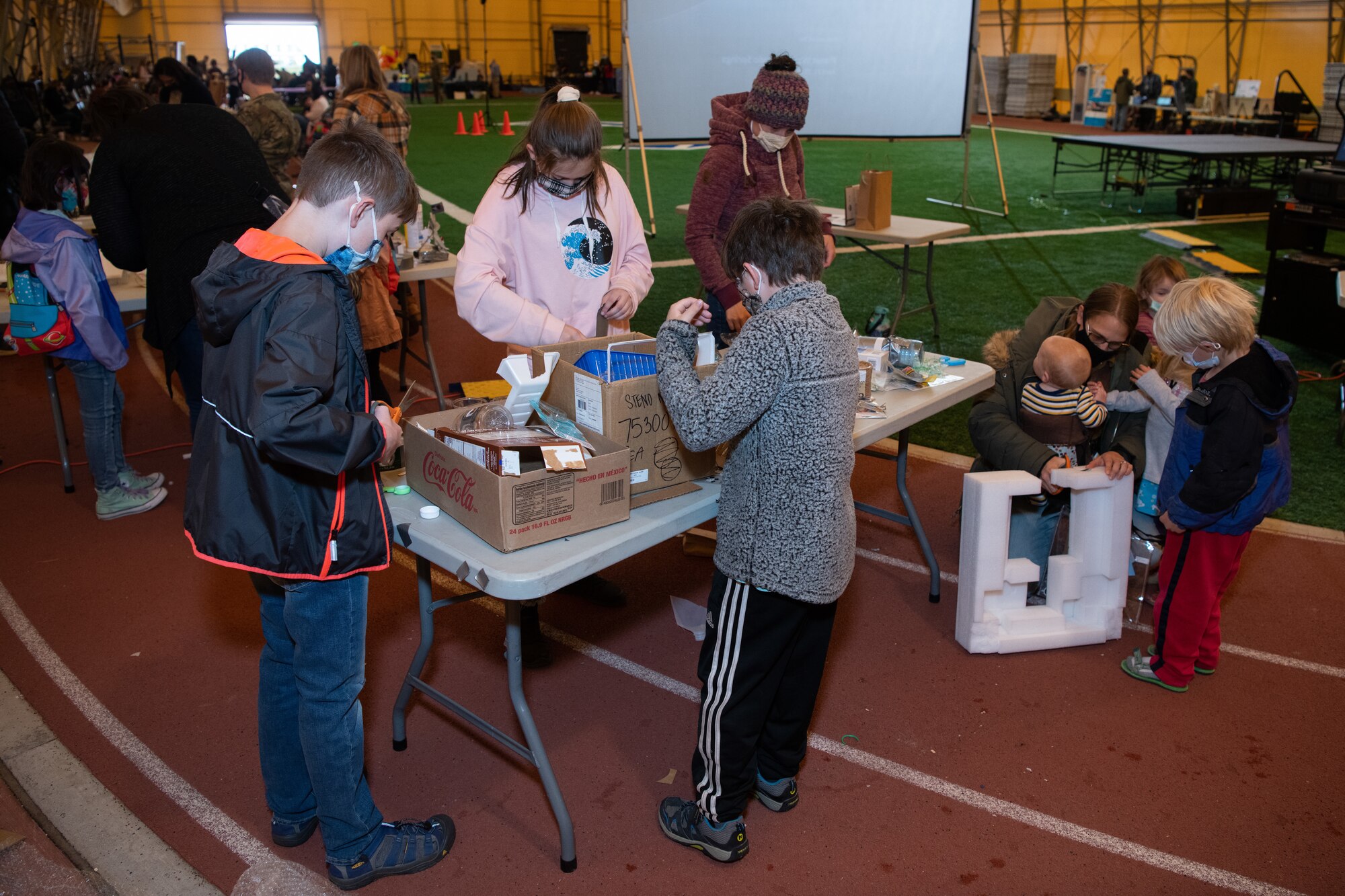 Kids and adults using scrap material to create floating boats during the STEAM event at Schriever Air Force Base