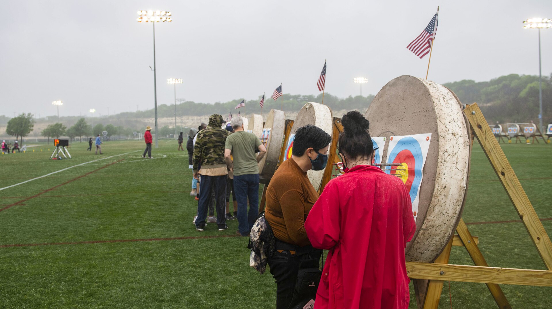 Participants, men and women, look and score targets and pull arrows.