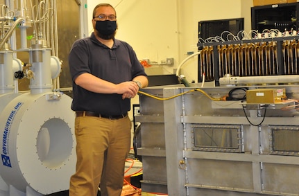 IMAGE: Naval Surface Warfare Center Dahlgren Division (NSWCDD) engineer Dr. Jon ‘Cameron’ Pouncey stands next to a pulsed power system used for the development and testing of novel high power microwave devices. Pouncey – principal investigator of a new project called the Micro-Laser Triggered Switches for Deployable Pulsed Power – is also the NSWCDD technical lead on three other high power microwave projects.