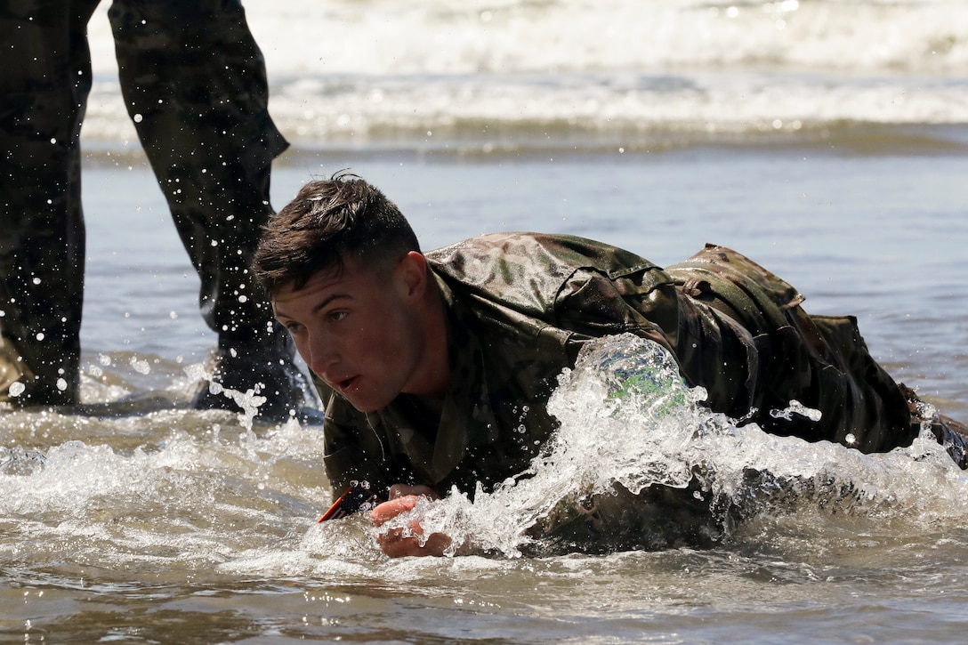 A soldier crawls on the beach.