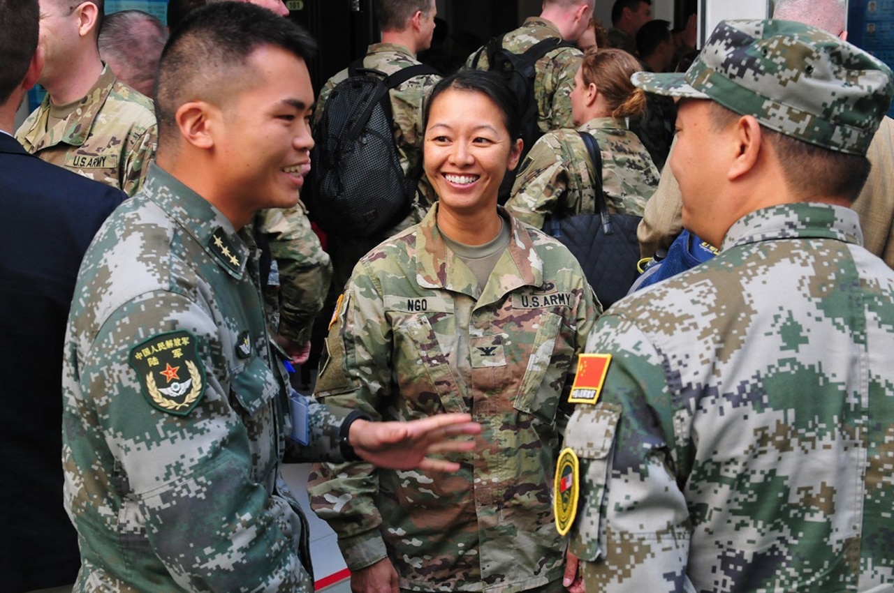 A group of people wearing military uniforms talk and smile.