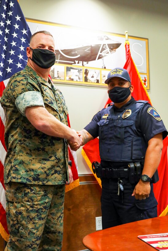 Col. Chuck Dudik and Military Police Officer Karl Bobbio shake hands after an award ceremony at Marine Corps Air Station (MCAS) Yuma, May 12, 2021. Officer Bobbio received the award for exemplifying high levels of professionalism, initiative and selfless dedication to the community of MCAS Yuma. (U.S. Marine Corps photo by LCpl. Matthew Romonoyske-Bean)